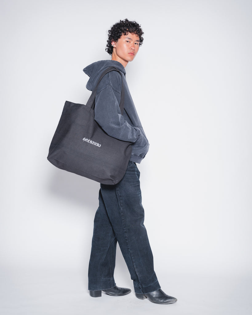 Model wearing recycled oversize black tote bag with Helsinki embroidery